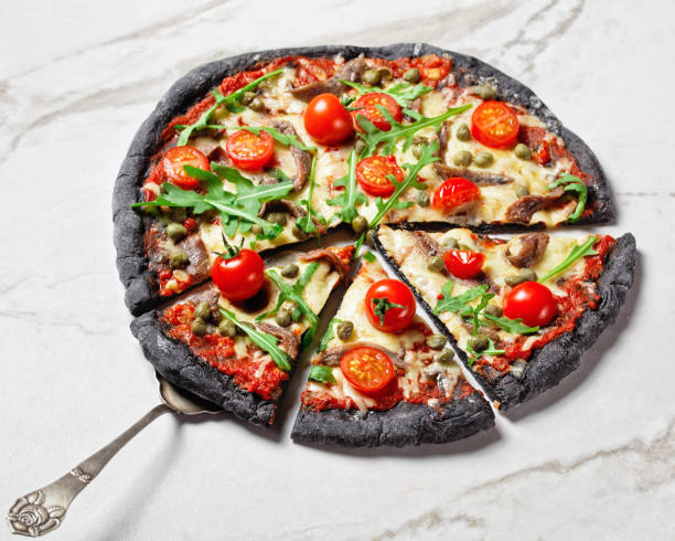 istock black dough pizza with jamon slices, mozzarella cheese, tomato, spinach leaves and red onion 1296847938