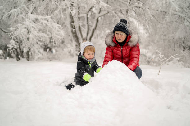 istock Mother with toddler son making snowman 1296852512