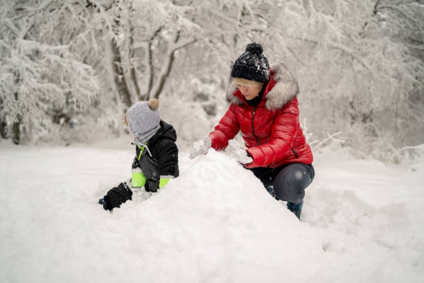 istock Mother with toddler son making snowman 1296852546