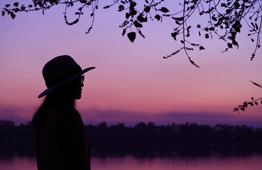 Silhouette of a woman in hat with dreamy purple evening sky in the backdrop, ( Self Portrait )