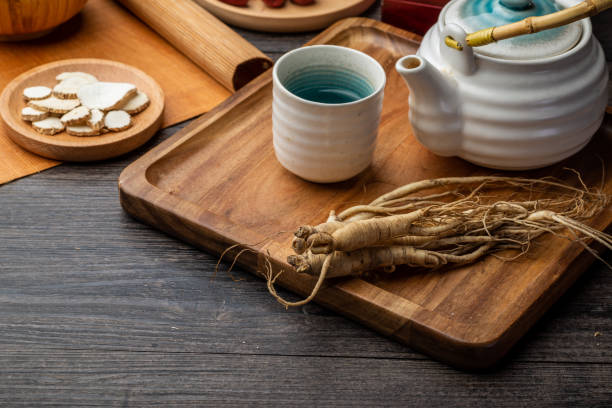 ginseng e tazza da tè sono sul tavolo - astragalus chinese medicine root plants foto e immagini stock