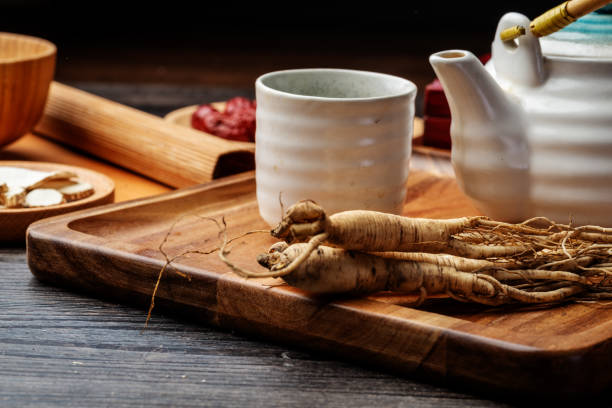 ginseng e tazza da tè sono sul tavolo - astragalus root foto e immagini stock