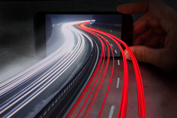 traffic highway light trails coming out of mobile phone showing the melting of virtual reality and the real world - real world imagens e fotografias de stock