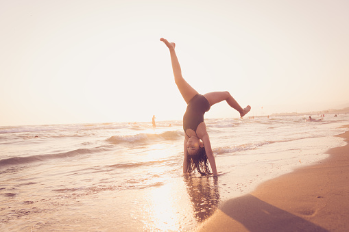 teenage Girl practicing gymnastics at the beach