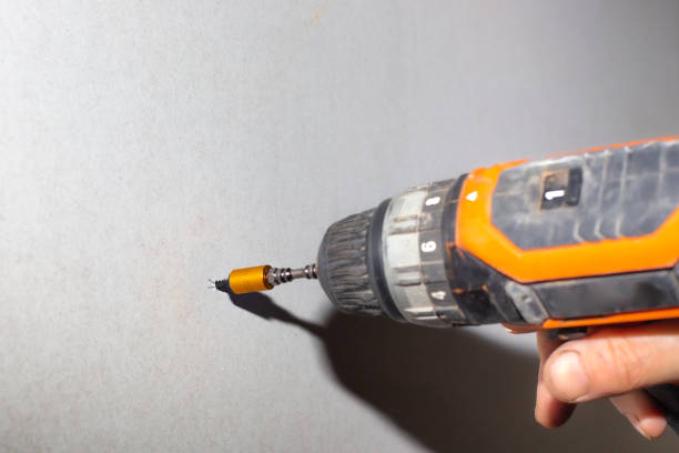 istock A man uses a screwdriver to screw a screw into a drywall. Home renovation, wall cladding 1296859459