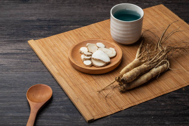 ginseng e tazza da tè sono sul tavolo - astragalus chinese medicine root plants foto e immagini stock