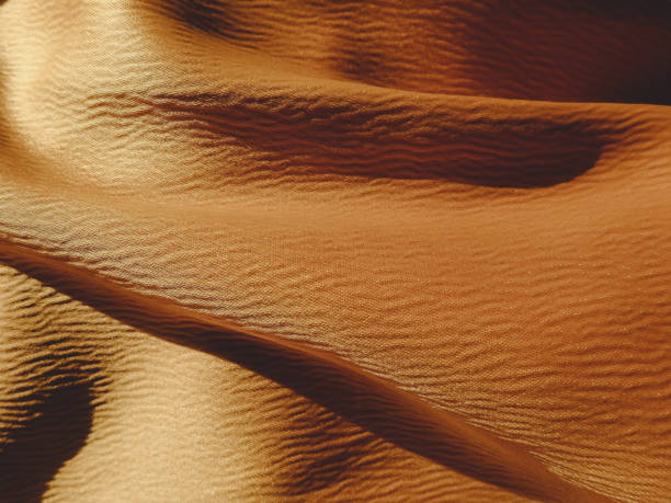 istock Gold camel color silk wavy texture background 1296862126