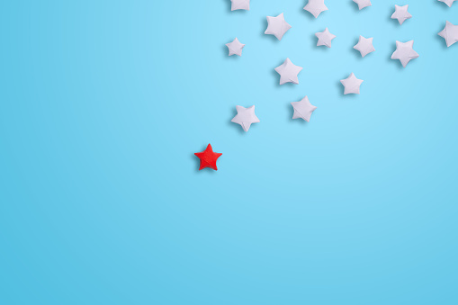 Red paper star leadning group of white on blue background
