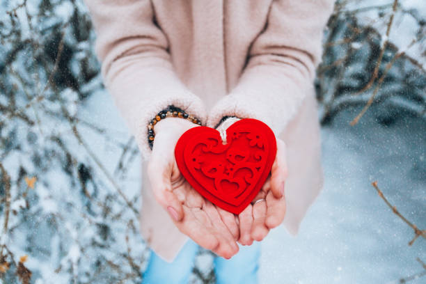 istock red heart valentine in hands on snowy background 1296863299