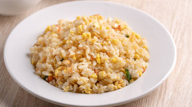 istock Chinese fried rice in white plate on bright wooden table background. 1296863327