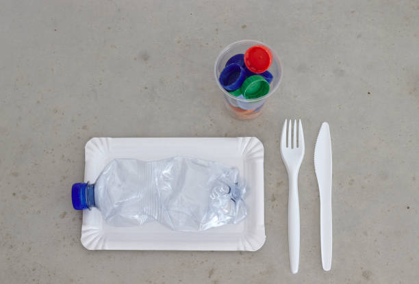 istock Plastic garbage on a plate, next to fork, spoon and cup filled with plastic bottle tops. Environment pollution concept and plastic pollution. 1296863976