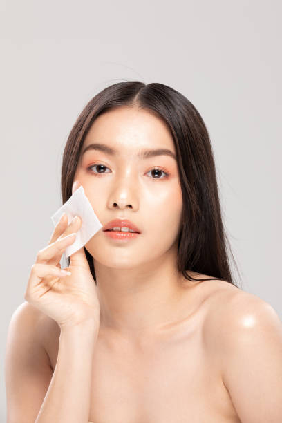 istock Attractive Charming Asian young woman smile and using tissue with toner for cleaning make up feeling so fresh and clean with healthy skin,isolated on white background,Beauty Cosmetics Concept 1296864329
