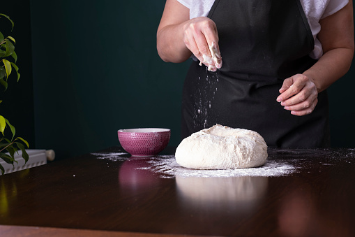 Closeup of woman rolling out dough with rolling pin on a table