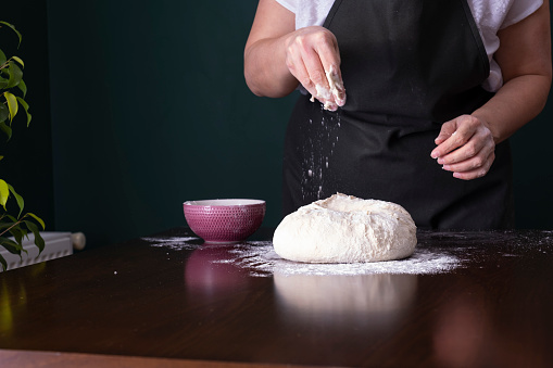 Old male Hands close-up man making dough for homemade noodles, dumplings on wooden board with wheat flour