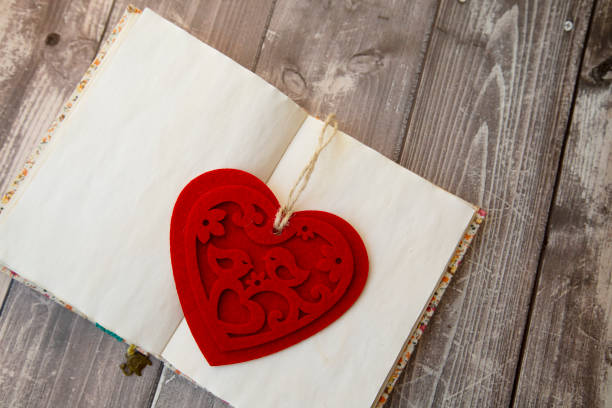 bookmark in the form of a red heart made of felt in a vintage notebook bookmark in the form of a red heart made of felt in a vintage notebook book heart shape valentines day copy space stock pictures, royalty-free photos & images