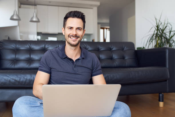 istock Portrait of smiling man using laptop at home 1296869716