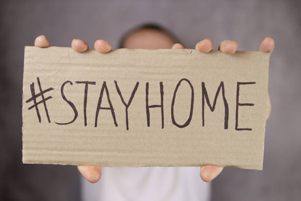 istock Hand holding a stay home poster on a gray background 1296872187
