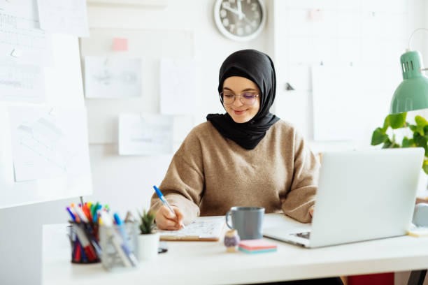 istock Middle Eastern interior designer working on laptop in office after covid-19 pandemic 1296872830
