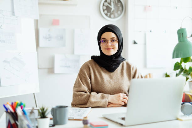 istock Middle Eastern woman working on laptop in office and looking at camera 1296872832