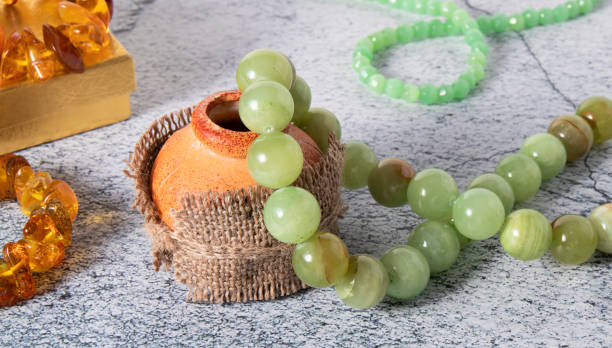 beautiful beads made from natural green-yellow onyx, agate  (layered chalcedony) stone with jade beads and baltic amber jewelry on a gray surface. - jade imagens e fotografias de stock