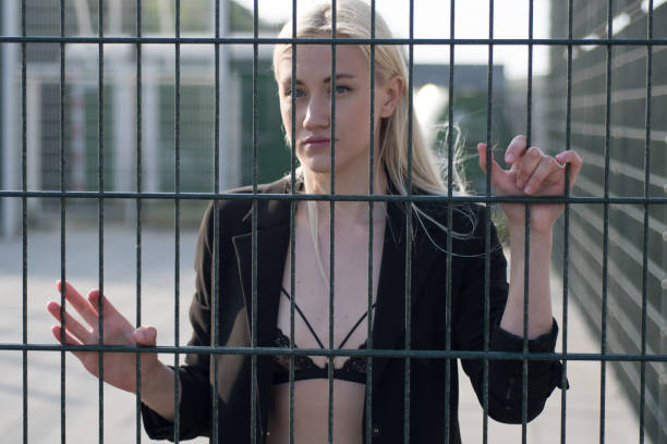 istock Blonde in a black bikini swimsuit behind a fence 1296875206