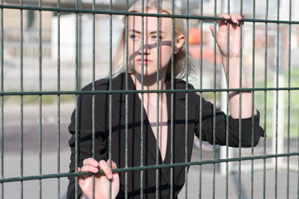istock Blonde in a black bikini swimsuit behind a fence 1296875219