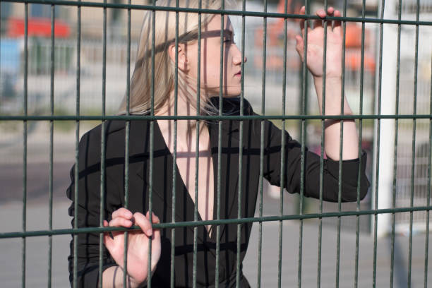 istock Blonde in a black bikini swimsuit behind a fence 1296875231