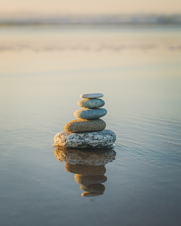 Pyramid of stones on the beach at sunset. Tranquil scene, relaxation, seaside vacation, meditation concept, copy space