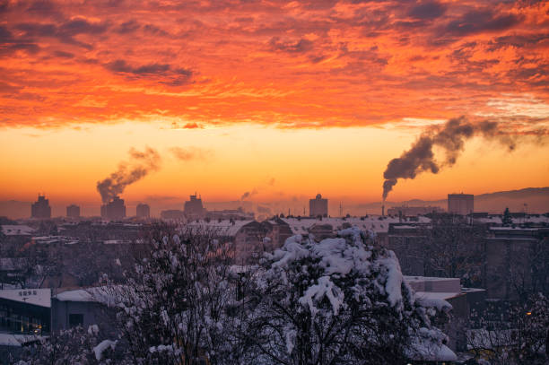 Overview of city skyline at the winter time with many smoking chimneys in the early morning
