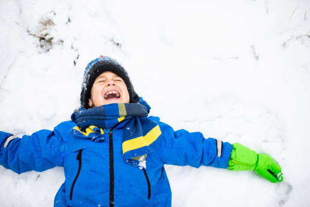 istock A cute boy lying in the snow with his mouth open to taste a snowflake 1296878430