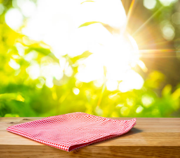 istock Red checked tablecloth on wood with blur green bokeh of tree background 1296881411