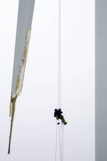 istock Rope access technicians rappelling down around wind-turbine blade and doing inspection 1296881469
