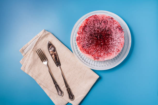 istock Diet low-calorie raspberry sponge cake with jelly, whipped cream and fresh berries with cutlery on blue background 1296881847