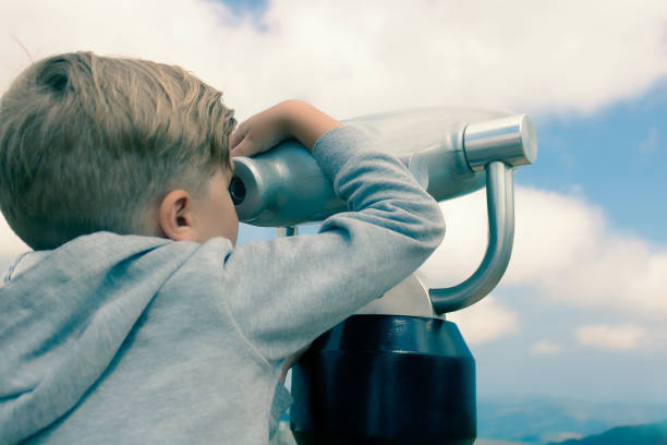 istock Curious kid  looking through coin operated binoculars against the sky. 1296887481