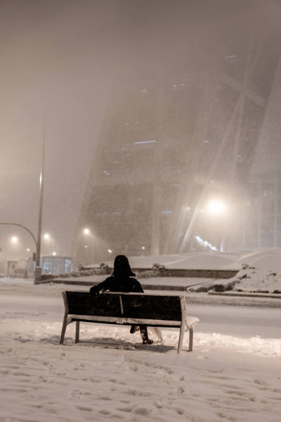 istock Woman in dark coat standing  during snowfall in Madrid. 1296888331