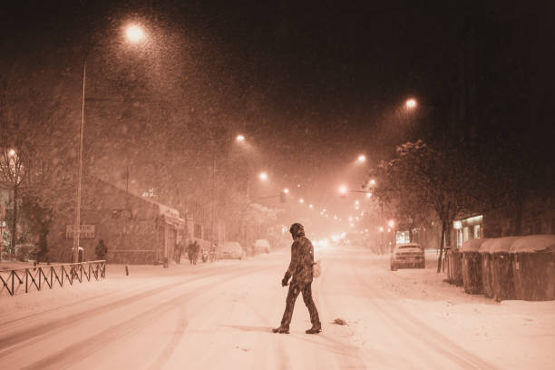 One man, young homeless man holding acoustic guitar, walking away, rear view.