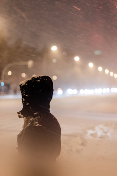 istock Woman in dark coat standing  during snowfall in Madrid. 1296888503