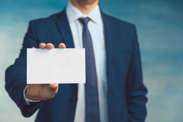 Male hand of a businessman in a blue suit with a tie holds an empty sheet in his hand and shows it to the camera closeup Male hand of a businessman in a blue suit with a tie holds an empty sheet in his hand and shows it to the camera closeup. male is standing and shows outstretched hand with open palm stock pictures, royalty-free photos & images
