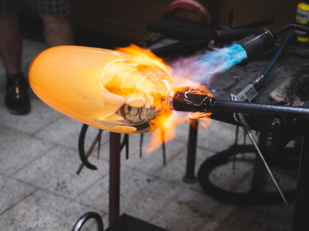 istock Artisan working with malleable glass and heating it with gas burner. 1296901807