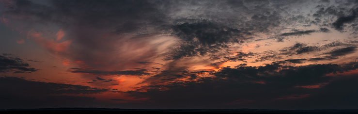 dramatic gloomy panorama of bright saturated sunset with many dark clouds