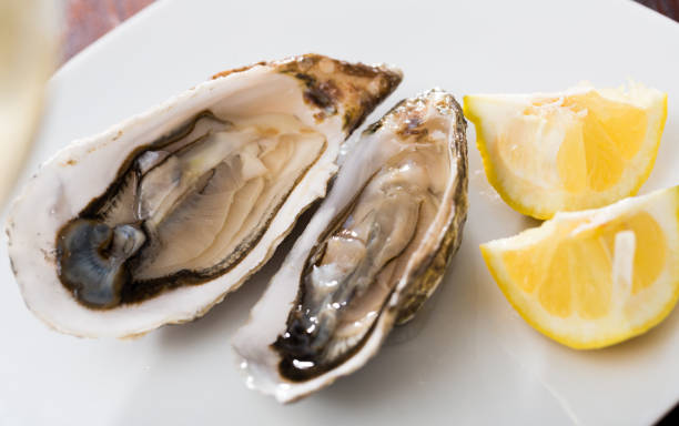 istock Tasty oysters with lemon on plate top view 1296902161