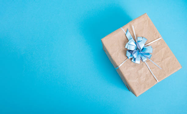 istock gift box made of craft paper with a blue bow on a blue background 1296904008