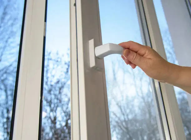 Hand opens vinyl plastic window on blue sky winter background. Oneped window.