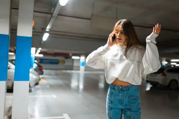 Girl after shopping discovered the loss of her automobile. Angry woman talking about missing car on phone. Vehicle theft concept. Nervous female emotionally speaks on the phone