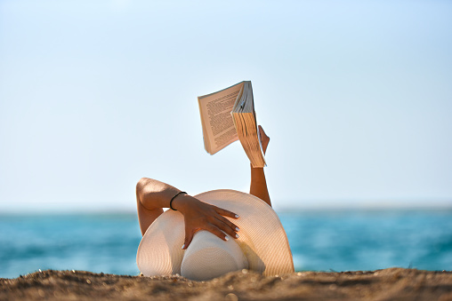 Young woman reads a book on the beach stock photo