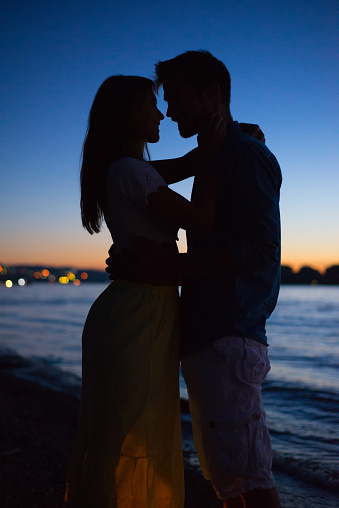 Silhouette of the young romantic couple on the beach at summer night.