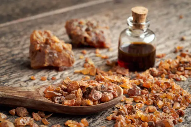 Myrrh resin on a spoon, with myrrh essential oil in the background