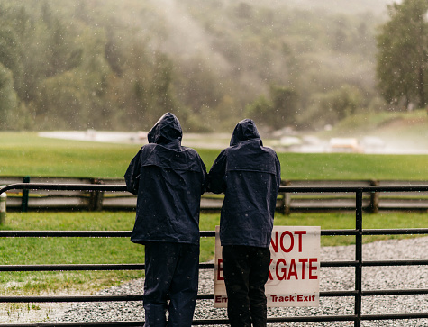 racing fans stand in rain coats in rain