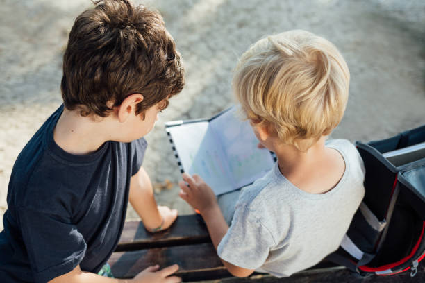 istock Two Boys Reading Notebook Outdoors 1296916597