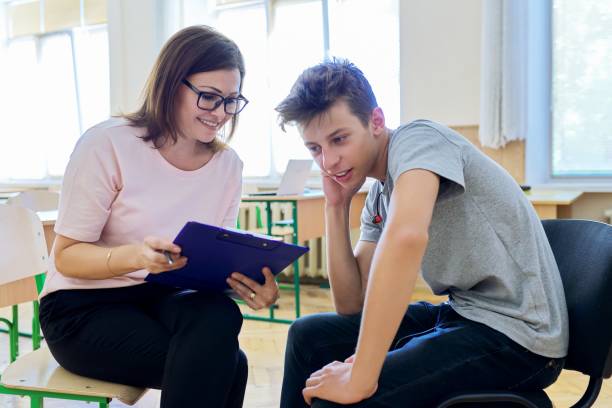 Woman school psychologist talking and helping student, male teenager Woman school psychologist talking and helping student, male teenager. Mental health of adolescents, psychology, social issues, professional help of counselor mental health kids stock pictures, royalty-free photos & images